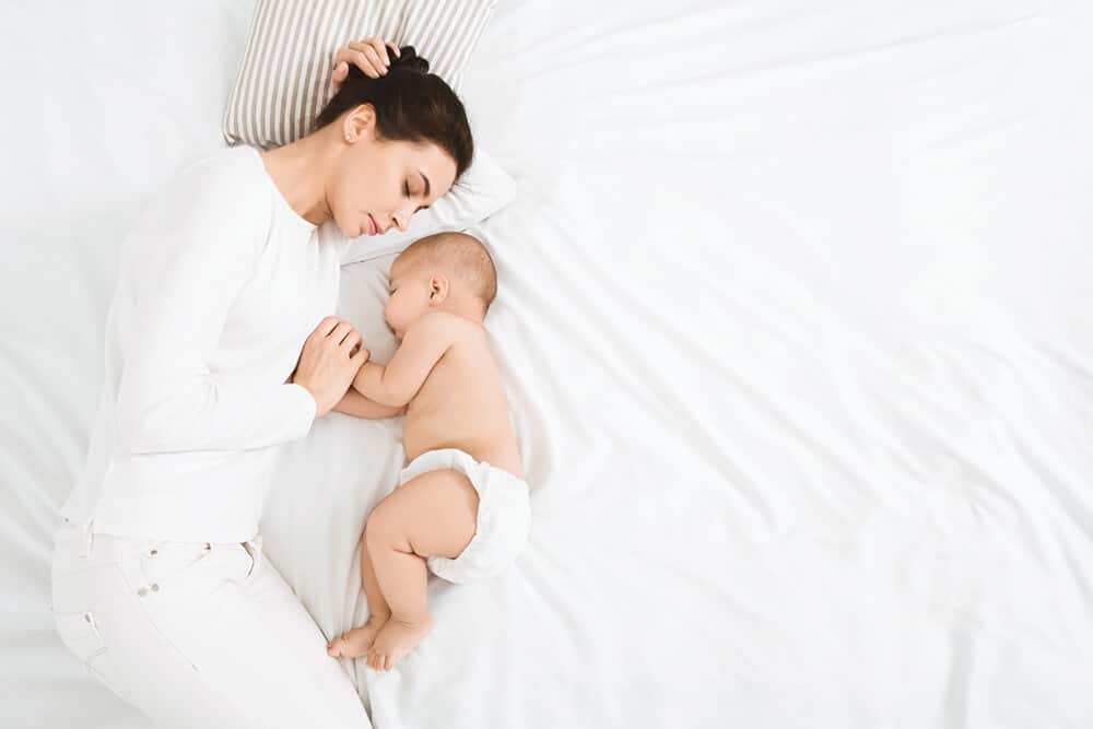 Mujer acostada con su bebe Disforia posparto